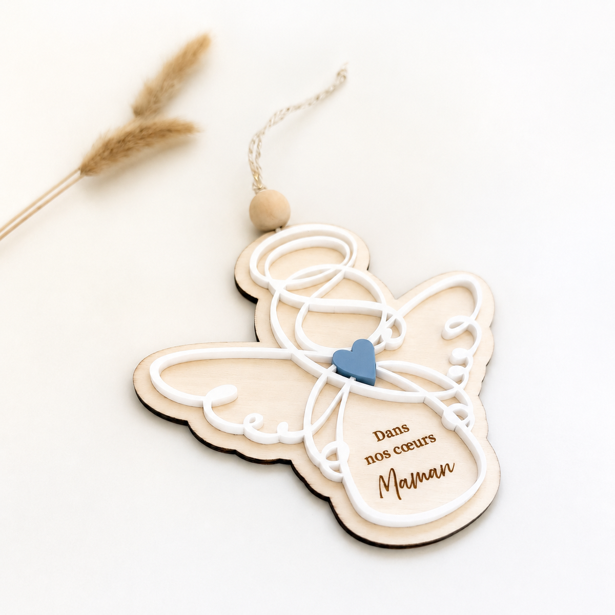 Cette suspension ange associe le bois naturel, un cœur bleu et une élégante gravure personnalisée. Une décoration souvenir unique et émouvante pour conserver près de soi la mémoire d’une maman.